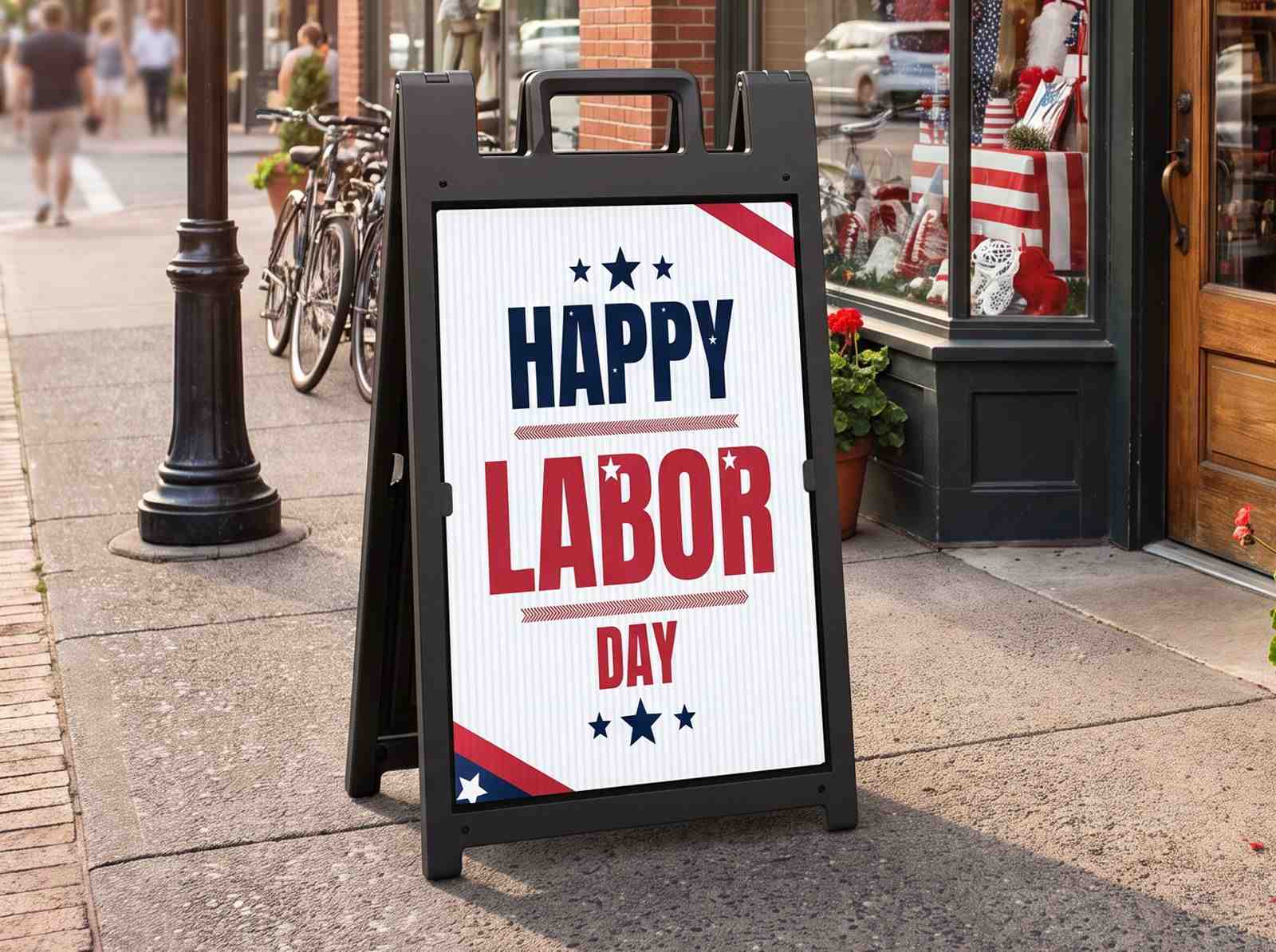 Black A-frame sidewalk sign displaying a patriotic "Happy Labor Day" message outside a storefront, attracting foot traffic and promoting seasonal sales, holiday events, and business specials.