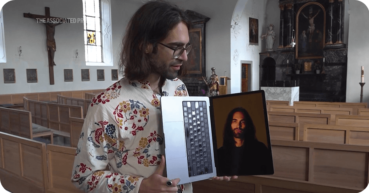 a man holding open a laptop with AI Jesus on the screen