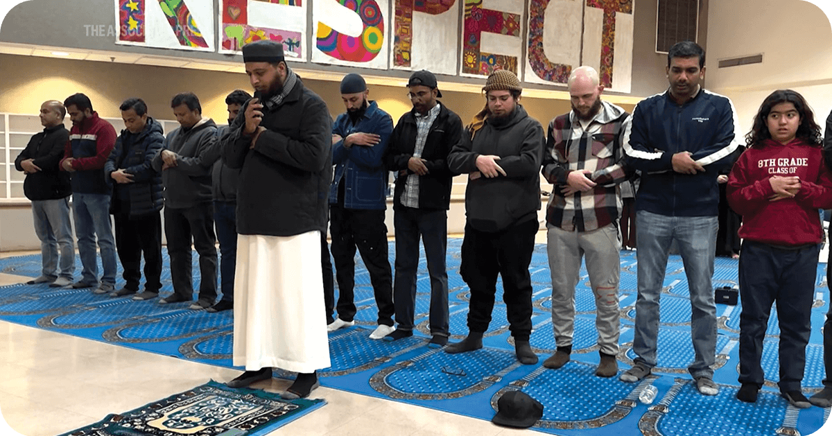 row of Muslims people praying in a large room